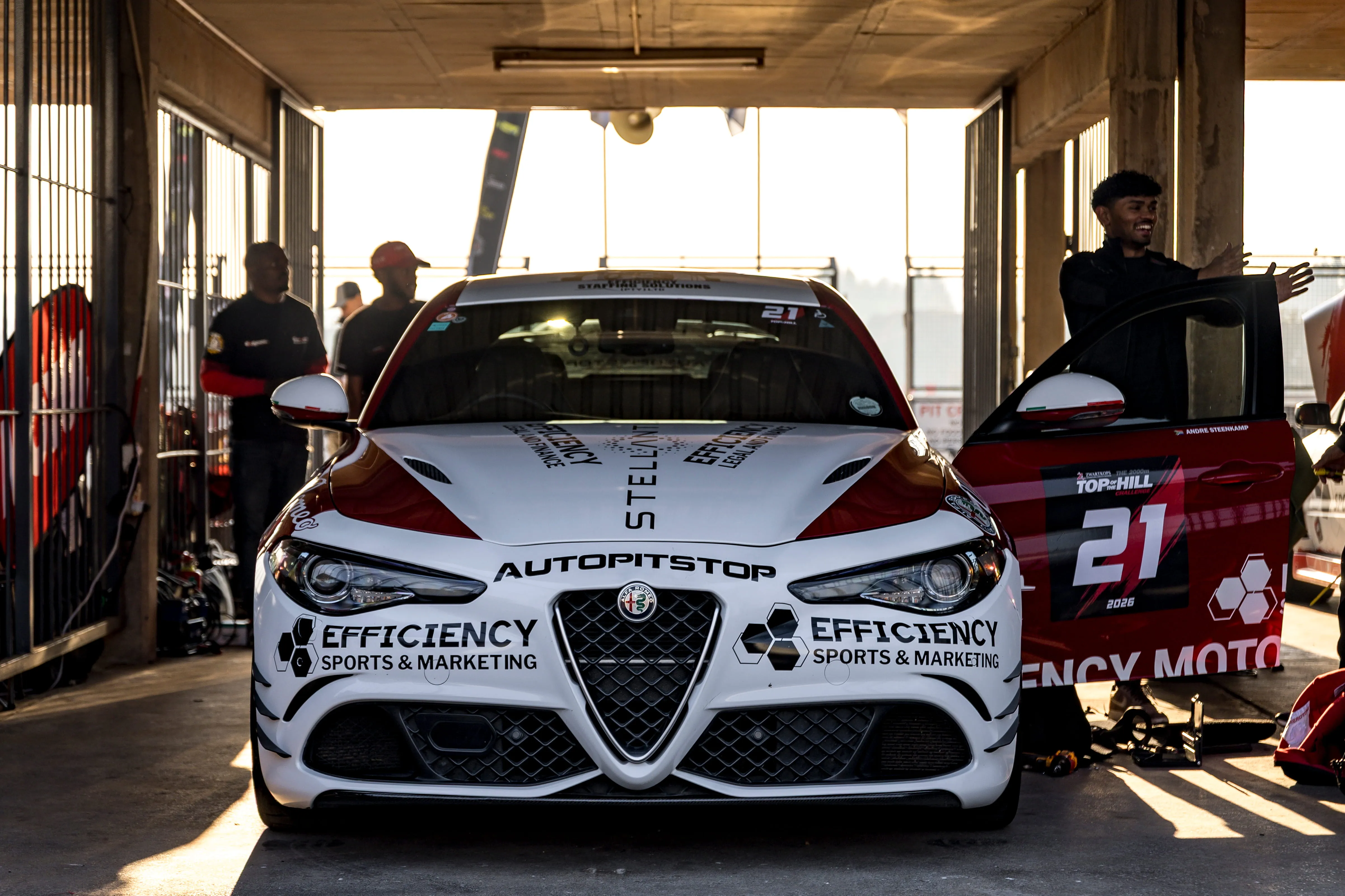Efficiency Motorsports Giulia in the pit garage with team activity around the car